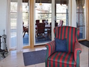 A room with a striped armchair, a wooden dining table, and chairs.