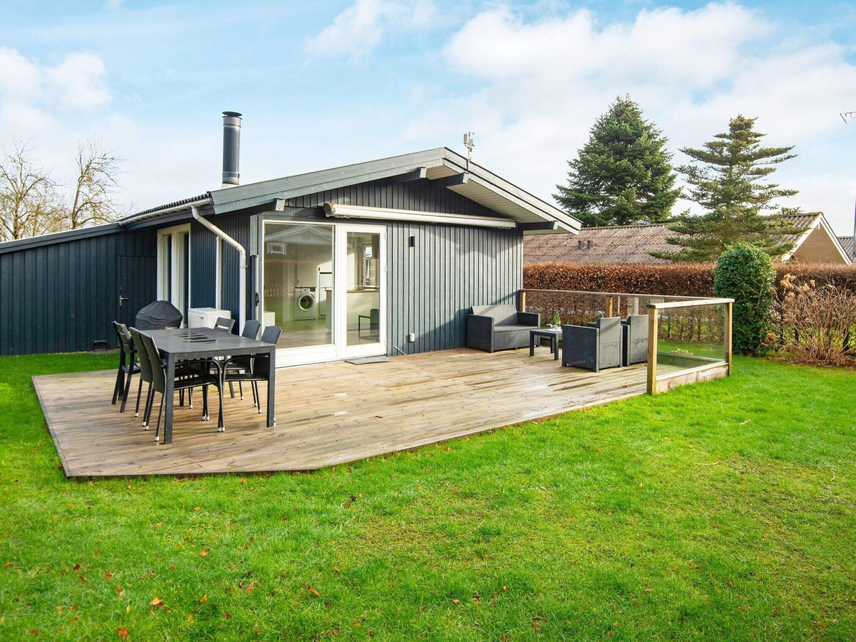 A modern house with a deck, outdoor seating, and a visible laundry area.