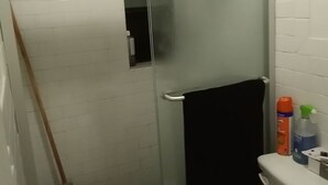 Une petite salle de bain avec une douche à parois de verre, des toilettes et un lavabo.