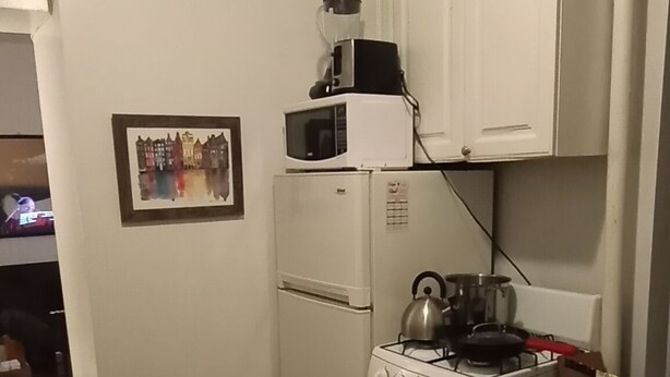 Une cuisine compacte équipée d’un réfrigérateur, d’un four à micro-ondes, d’une cuisinière et de placards.