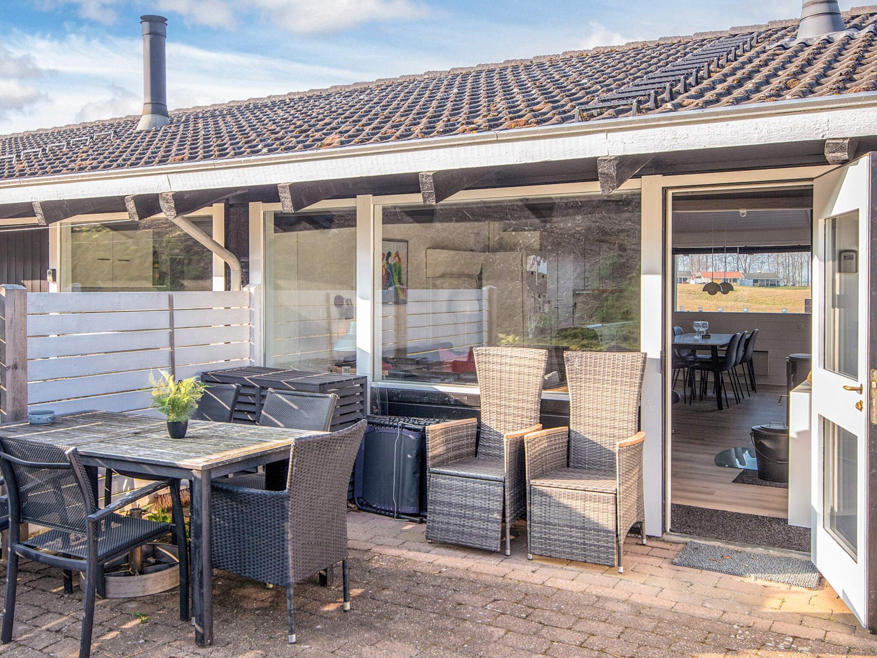 Una terrazza esterna con mobili in vimini, un tavolo e un'area coperta con tetto in tegole.