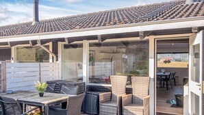 An outdoor patio with wicker furniture, a table, and a covered area with a tiled roof. - 5 Star Holiday Home in Aabenraa (Aabenraa)