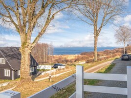 A coastal property with a gravel driveway, a white fence, and a view of the sea.