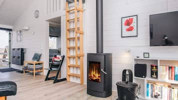 Una sala de estar moderna con una chimenea de leña, una estantería y una escalera.