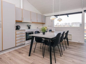 A modern kitchen with white cabinets, a dining table with black chairs, and pendant lights. - 5 Star Holiday Home in Aabenraa (Aabenraa)