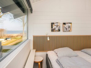 A bedroom with a large window, a bed, a small round table, and two wall-mounted paintings. - 5 Star Holiday Home in Aabenraa (Aabenraa)