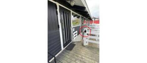 A wooden deck with a black awning, a white railing, and a red and white sign with a red circle.