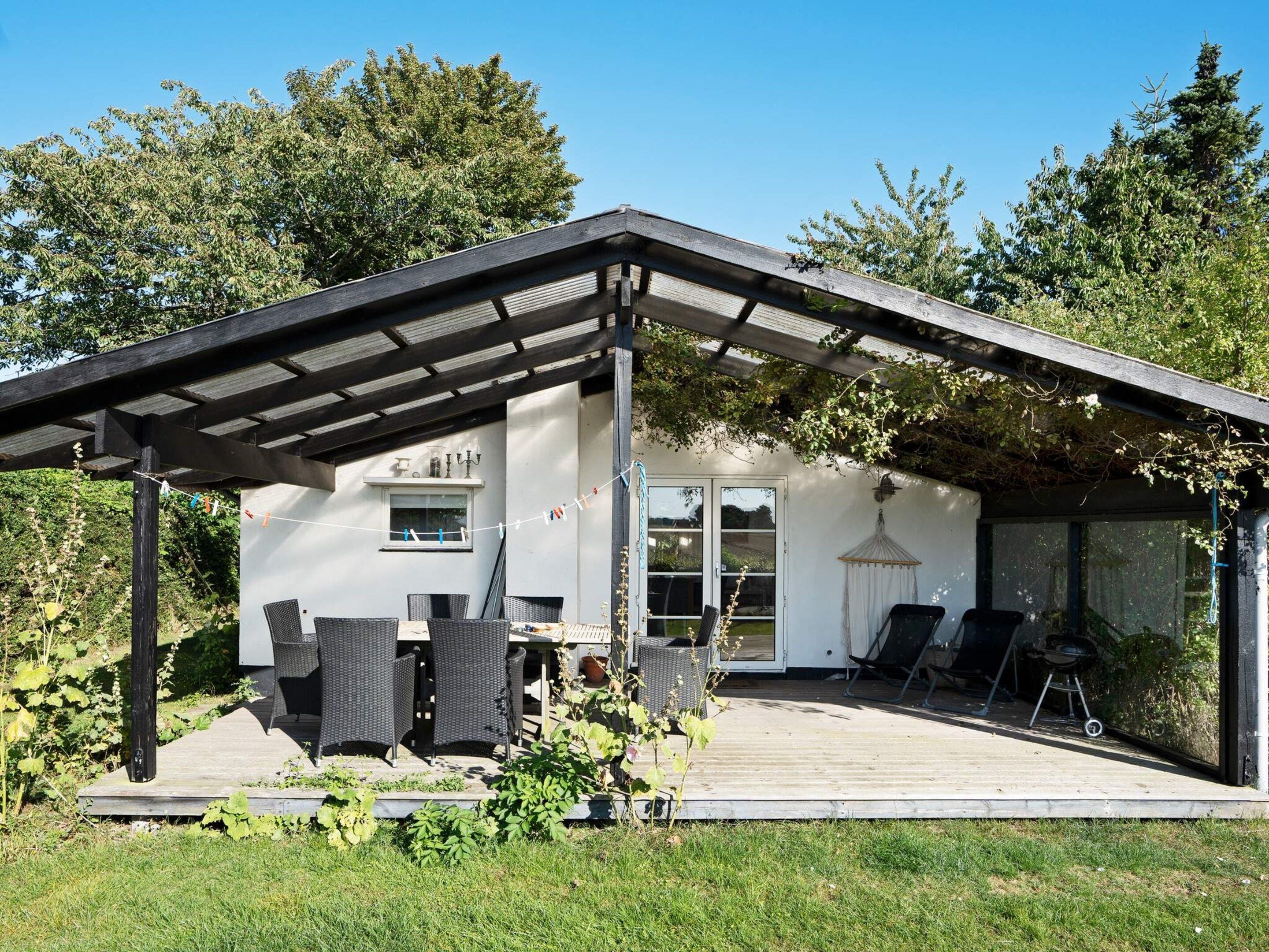 Una casa moderna con patio coperto, area salotto esterna e giardino.