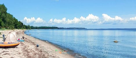 Una playa con una tienda de campaña y un bote en la orilla.