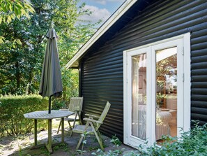 A wooden cabin with a sliding glass door, a patio table, and two chairs.