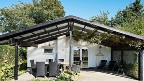 Une maison moderne dotée d’un patio couvert, d’un espace salon extérieur et d’un jardin.