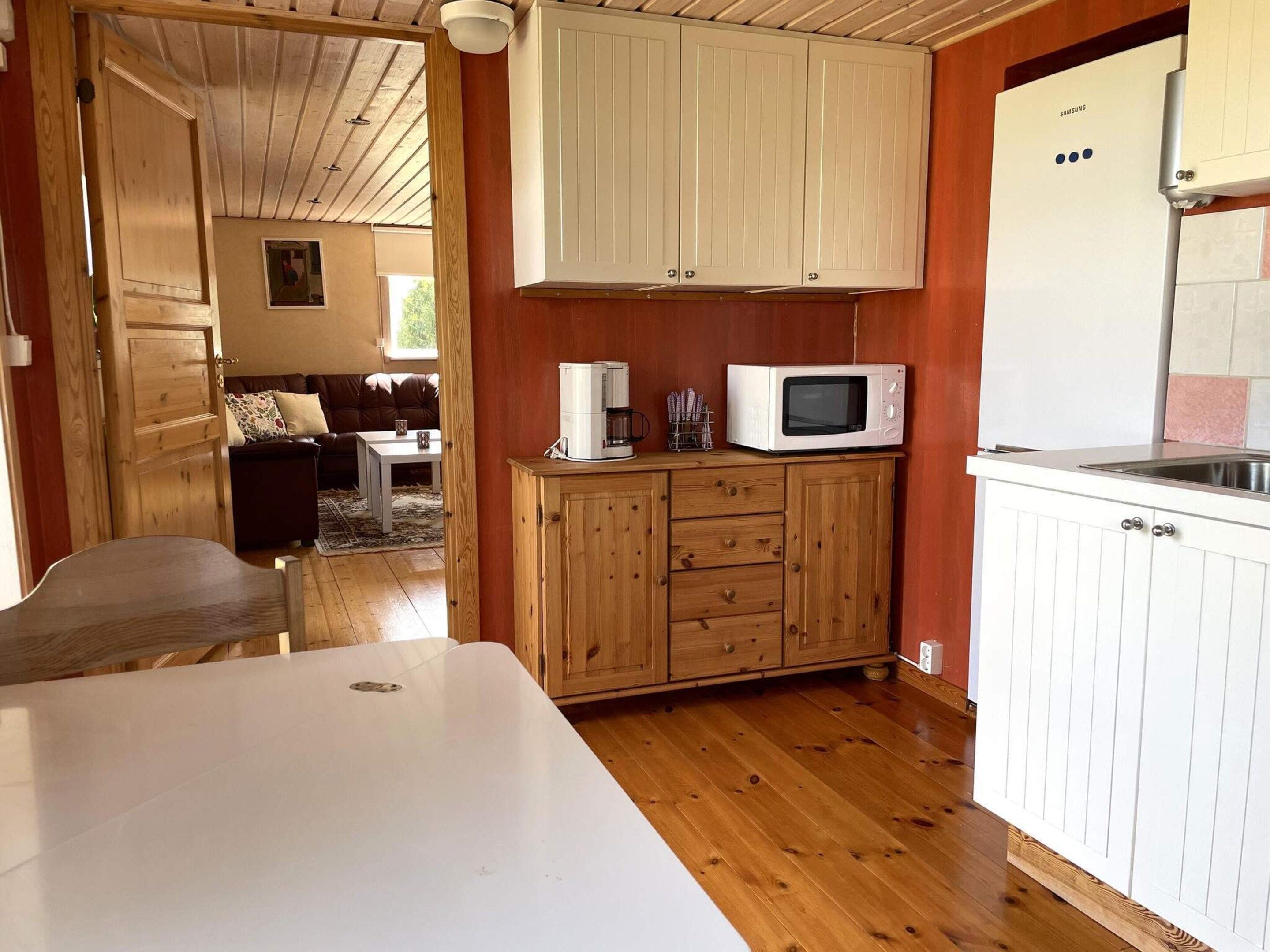 A compact kitchen with a microwave, coffee maker, and wooden cabinets.