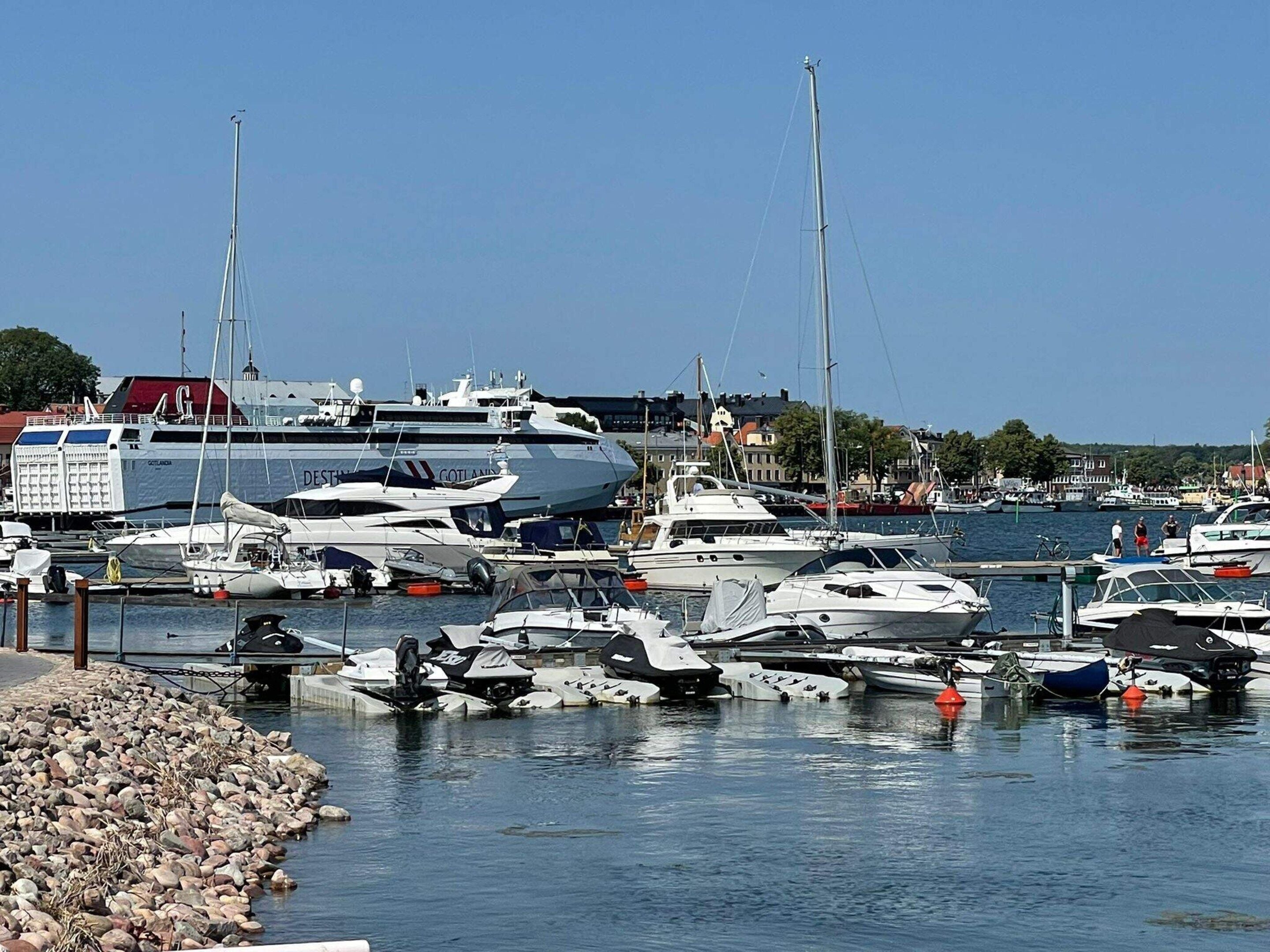 A marina with various boats docked, including a large yacht and smaller vessels.