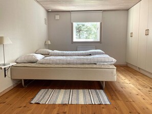 A bedroom with a bed, a window, a radiator, and a wooden floor. - 4 Person Holiday Home in Gamleby (Gamleby)