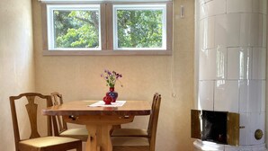 Een eetruimte met een houten tafel en stoelen, een vaas met bloemen en een witte open haard.