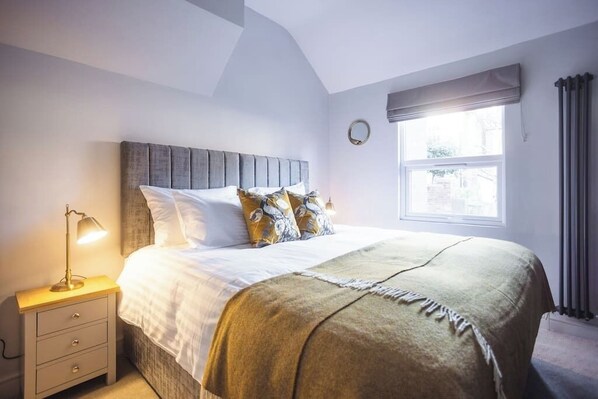 A bedroom with a bed, bedside lamp, and a window with curtains.