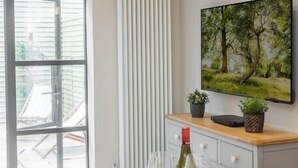 Eine moderne Küche mit einem großen Fenster, einem Heizkörper, einem Gemälde und einem Tablett mit Weingläsern und einer Flasche.