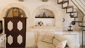 A living room with a sofa, a wooden cabinet, and a staircase. - TRULLI ALLEGRETTI (Private pool): your vacation in the heart of Puglia (Noci)