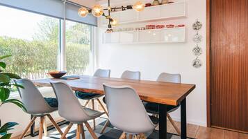 Un comedor con una mesa de madera, sillas grises y una lámpara colgante moderna.