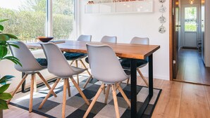 Un comedor con una mesa de madera, cuatro sillas y una lámpara de techo moderna.