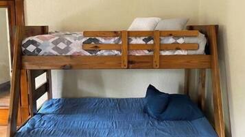 A bunk bed with a lower blue mattress and a top mattress with a patterned blanket.