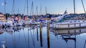 A marina with multiple boats docked, calm water, and buildings in the background. - 4 Person Holiday Home in Allinge (Allinge)