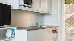 A modern kitchen with a built-in microwave, a sink, and a television on a shelf. - 4 Person Holiday Home in Allinge (Allinge)