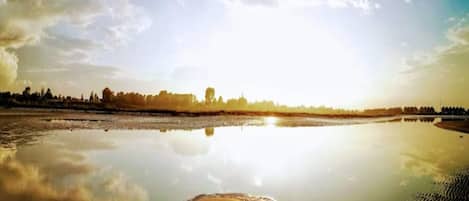 Ein weiter Fluss mit ruhigem Wasser, das Himmel und ferne Bäume spiegelt.