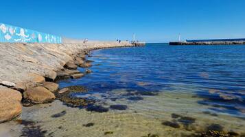 Un paseo marítimo con agua cristalina, rocas y un muelle.