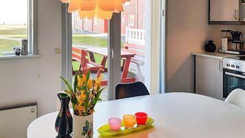 A modern kitchen with a dining table, a vase with flowers, and a view of an outdoor patio.