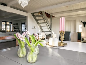 A modern kitchen with a white countertop, three glass vases with flowers, a candelabra with candles, and a staircase in the background. - 11 Person Holiday Home in Lokken-by Traum (Lokken)