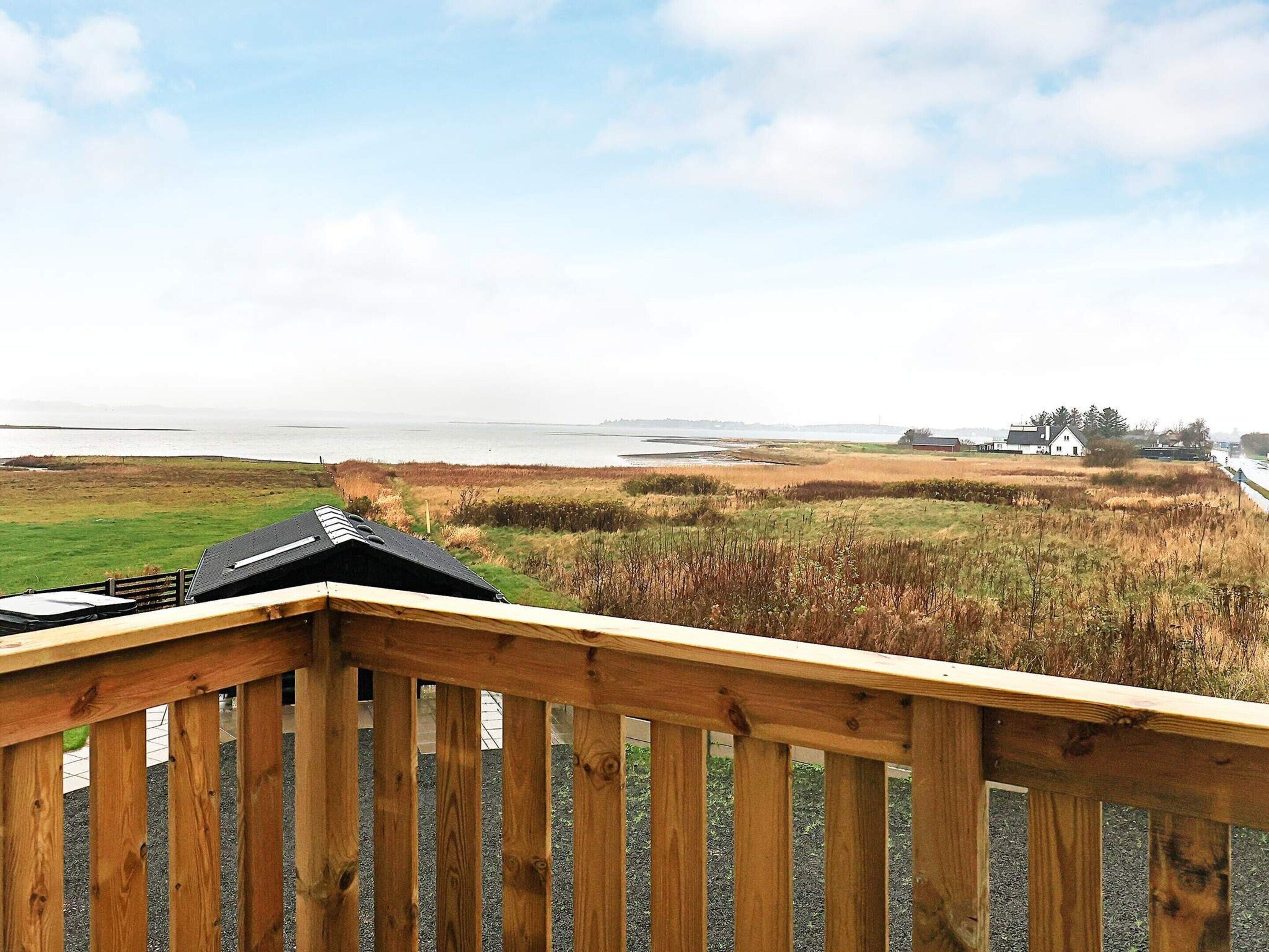 A wooden deck overlooking a coastal landscape with a view of the sea and distant buildings.