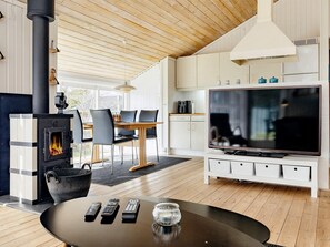 A modern living room with a fireplace, a dining area, and a TV.