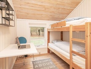 A compact room with a bunk bed, a desk with a laptop, and a window with a view of trees.