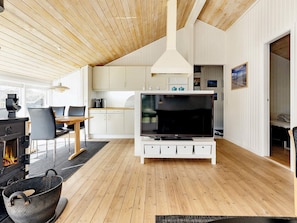 A modern living room with a fireplace, a dining area, and a kitchen.