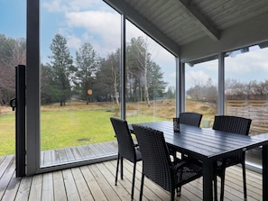 Une terrasse avec une table et des chaises, donnant sur un espace verdoyant avec des arbres.
