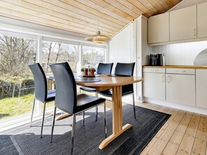 Une cuisine moderne avec des meubles blancs et une table à manger en bois, accompagnée de chaises.