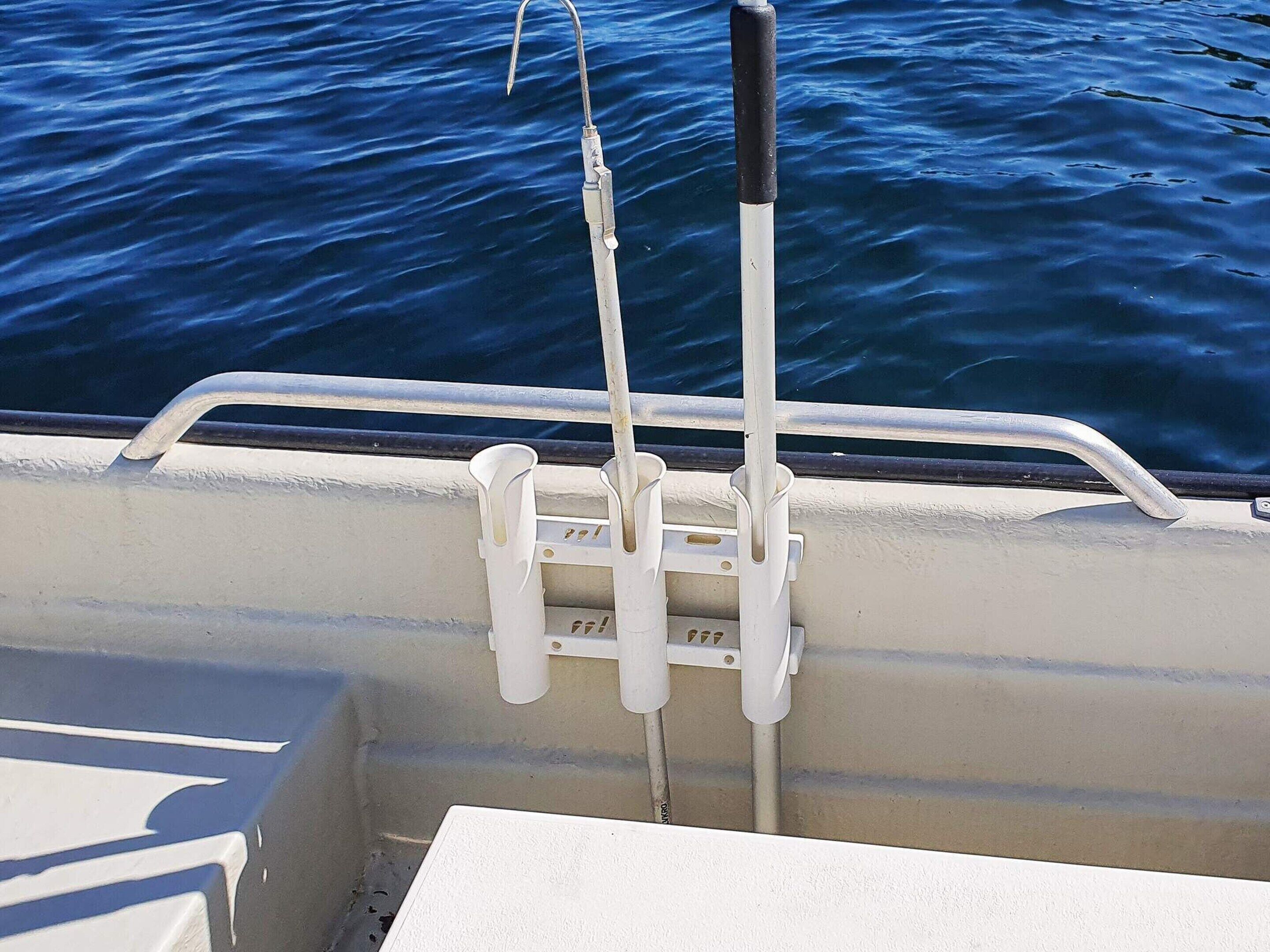 A boat's railing with a fishing rod holder and a metal rod.