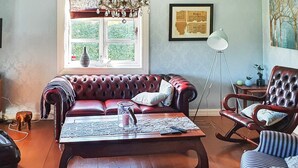 Ein Wohnzimmer mit einem roten Ledersofa, einem Holztisch und einem gestreiften Sessel.