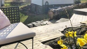 Eine Holzterrasse mit einem Stuhl, einem Felsen und gelben Blumen.