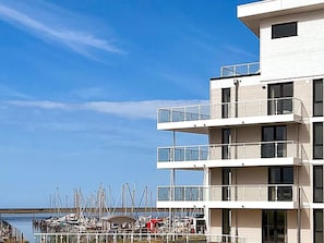 Um edifício com vários andares e varandas que dão para uma marina com barcos.