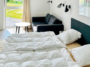 A hotel room with a bed, a sofa, a small table, and a view of the outdoors.