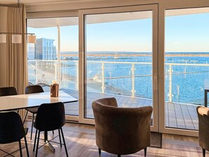 Quarto de hotel moderno com uma grande janela que oferece vista para uma marina e para a água.