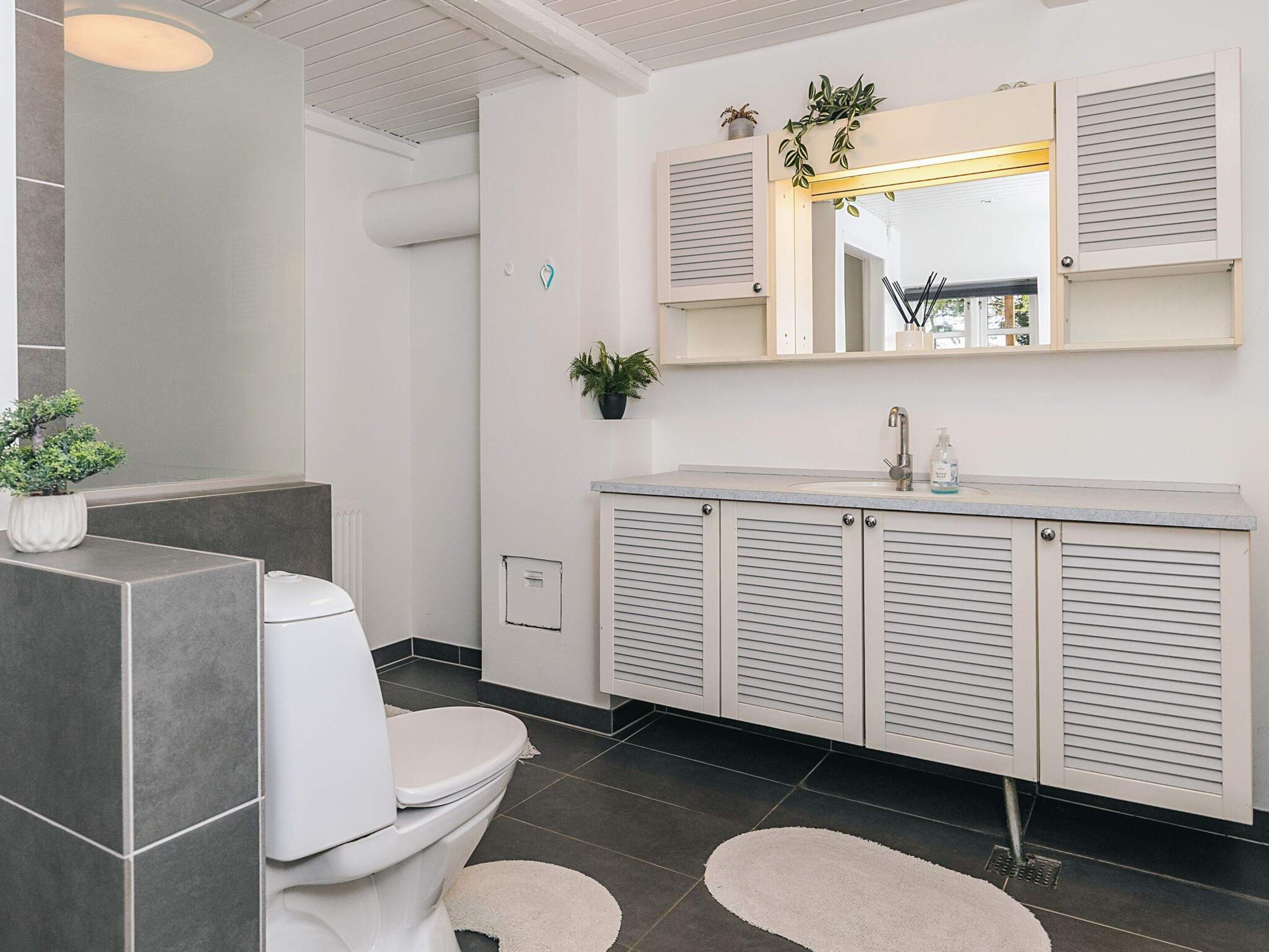 A modern bathroom with a toilet, sink, and mirror.