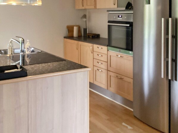 A modern kitchen with wooden cabinets, a stainless steel refrigerator, and a built-in oven. - 8 Person Holiday Home in Sakskobing (Sakskobing)