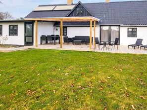 Una casa moderna con un porche cubierto, césped y una terraza.