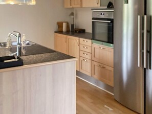 A modern kitchen with wooden cabinets, a stainless steel refrigerator, and a built-in oven. - 8 Person Holiday Home in Sakskobing (Sakskobing)