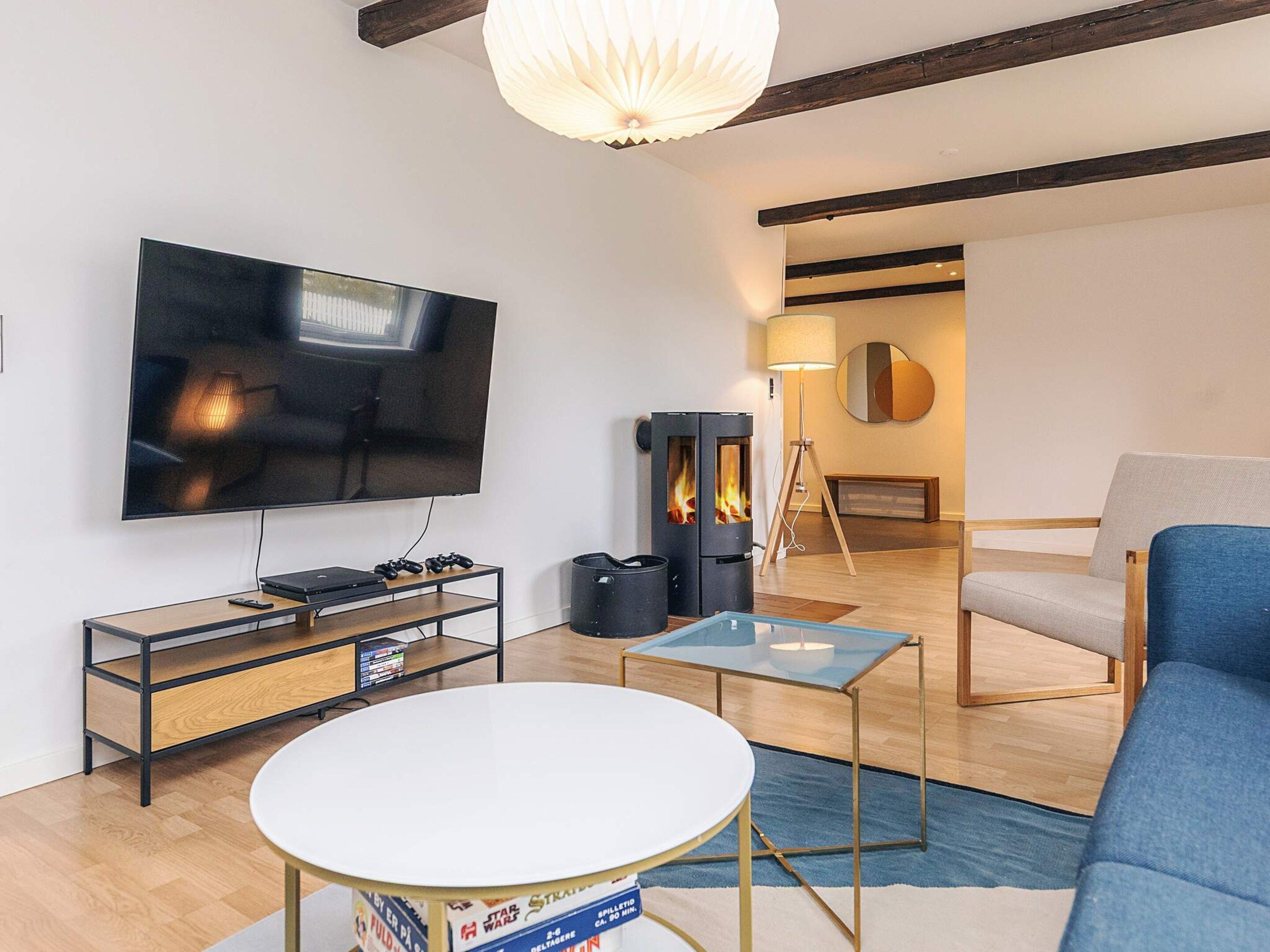 A modern living room with a flat-screen TV, a gaming console, a round coffee table, and a blue sofa.