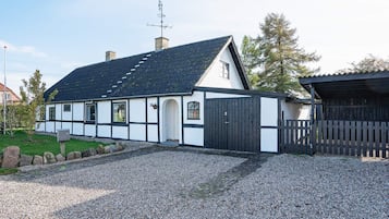 Una casa tradicional de entramado blanco y negro con un camino de grava y una valla de madera.