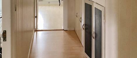 A hallway with a wooden floor leading to a room with a white door and a cabinet with black doors.
